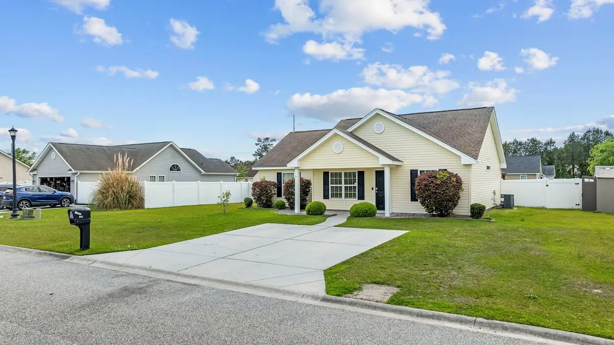 Single-story home with broad driveway, lawn, and pale siding