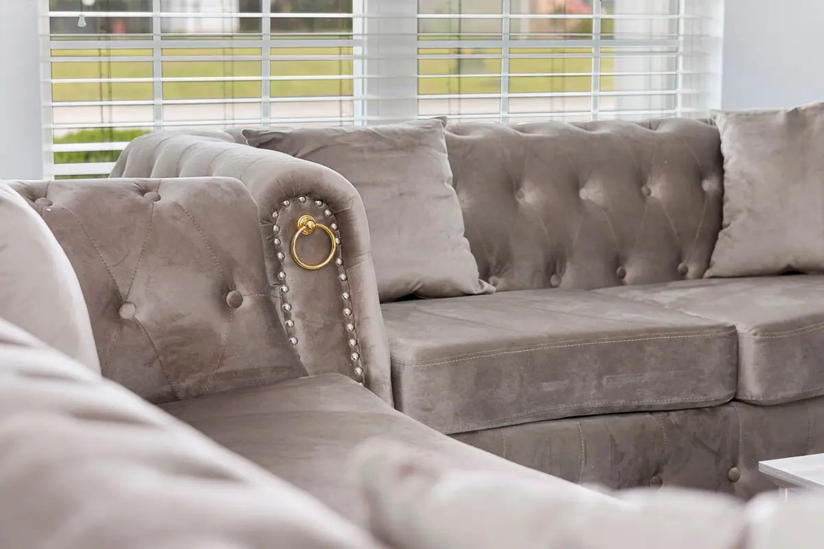 Close view of tufted gray sofa beside a sunlit window