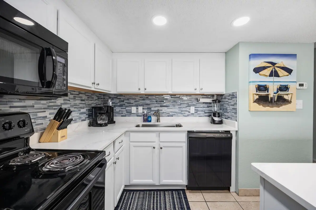 White kitchen with dark appliances and a gray tile backsplash
