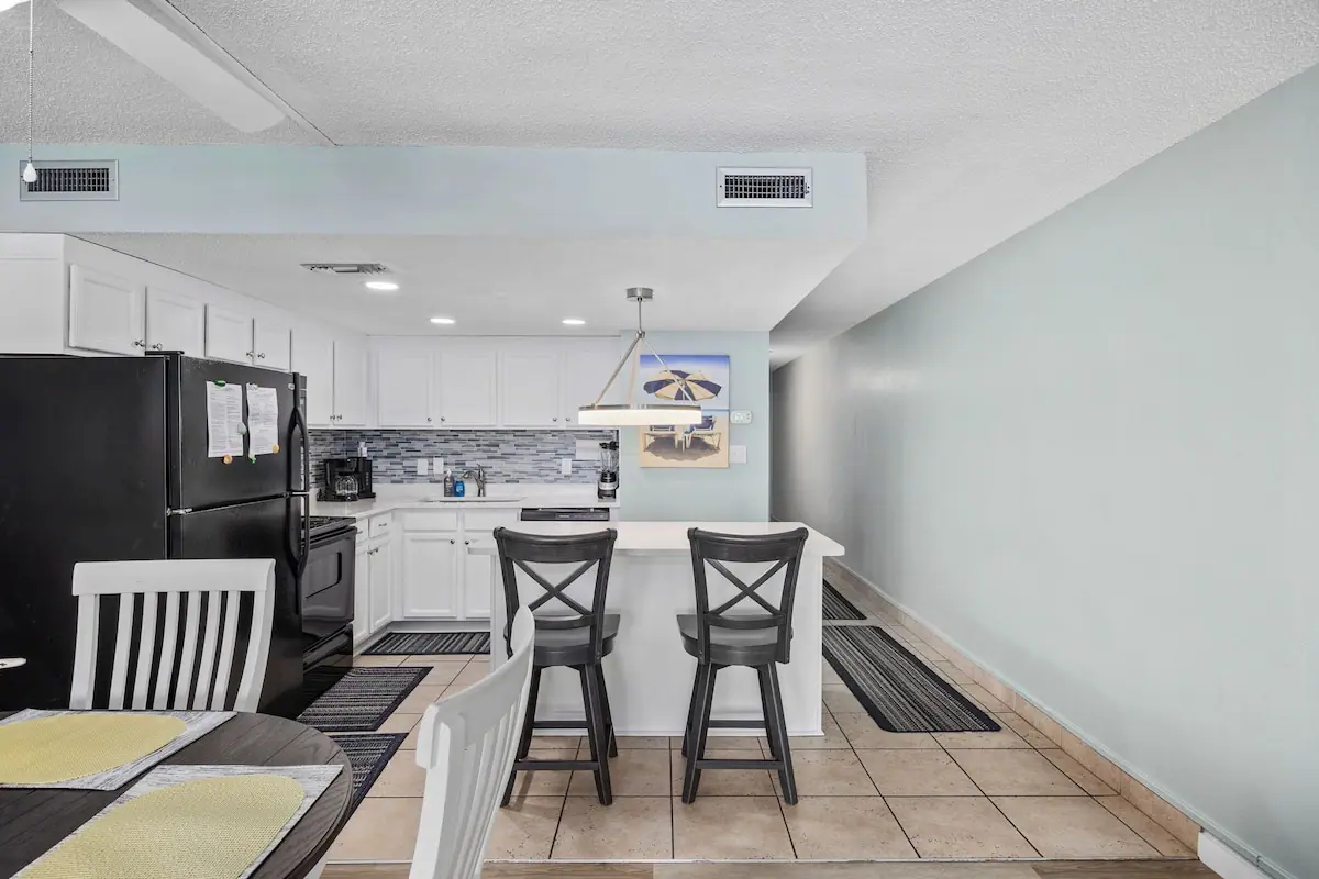 White kitchen breakfast bar with two stools beside the dining table
