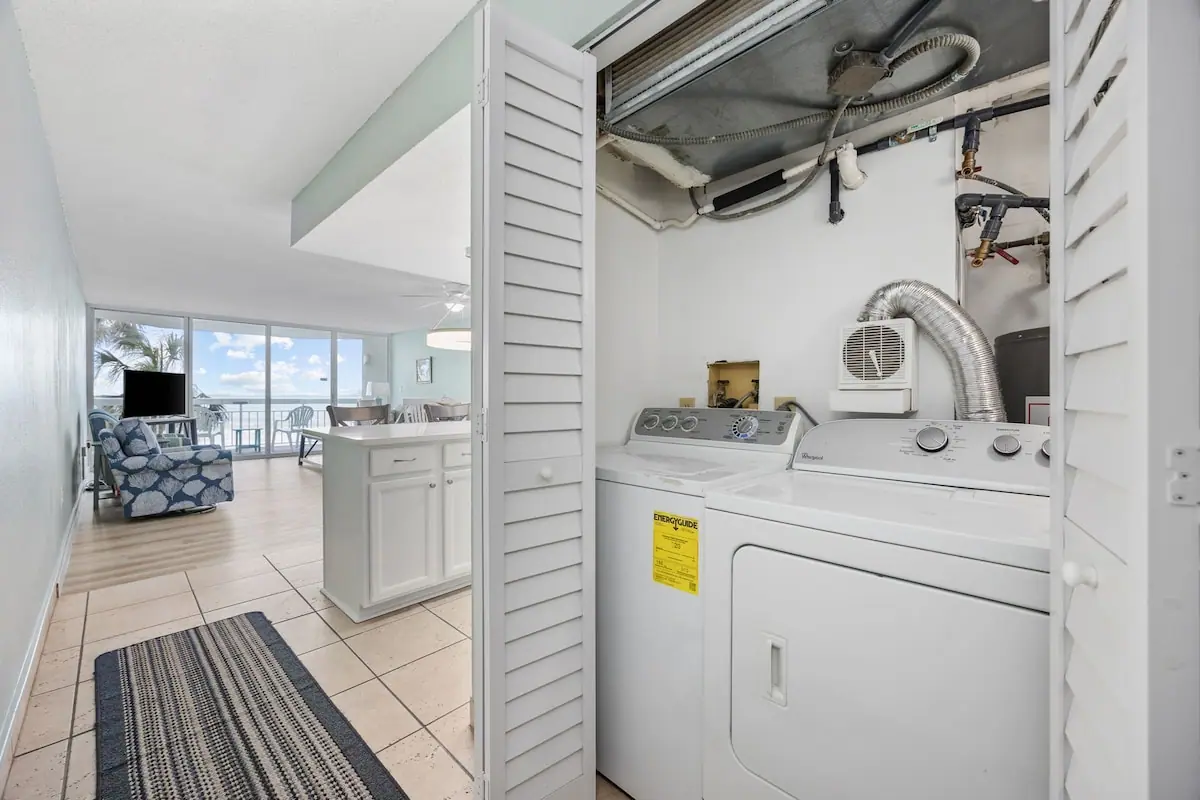 Washer and dryer in a hallway closet with the living room beyond