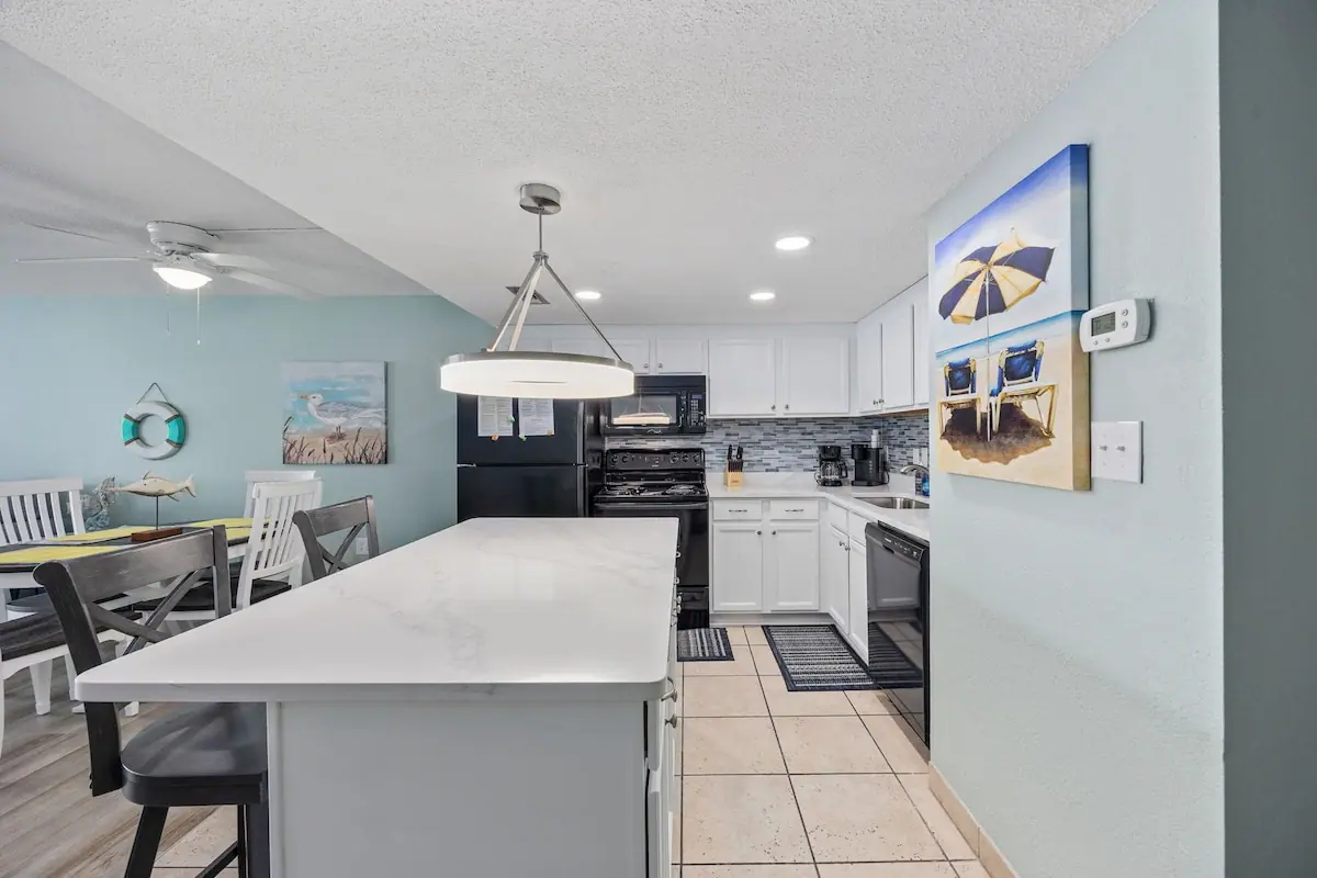 White kitchen island with dining table and living room beyond