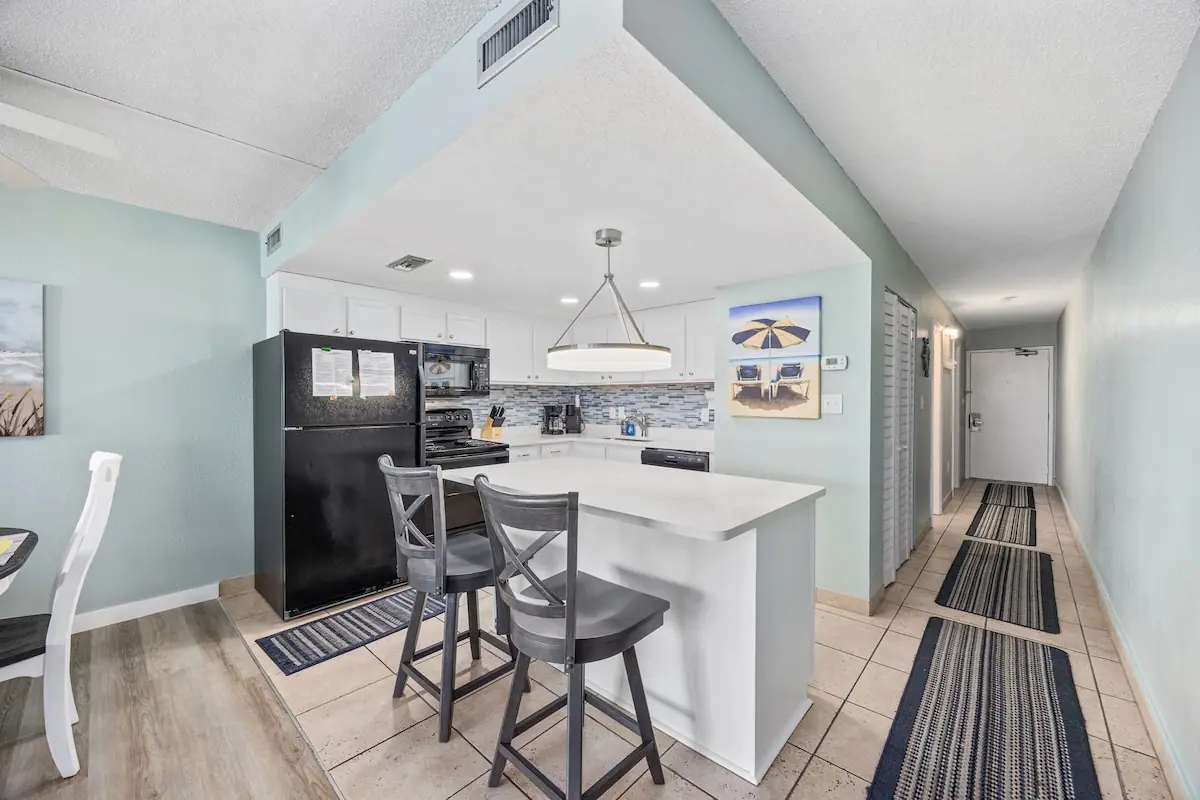 Kitchen breakfast bar with two chairs beside a long hallway