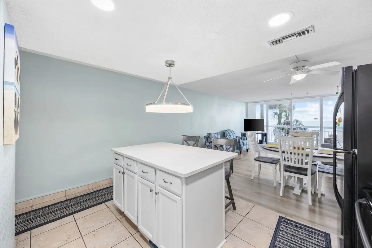 White kitchen island with dining table and glass doors beyond
