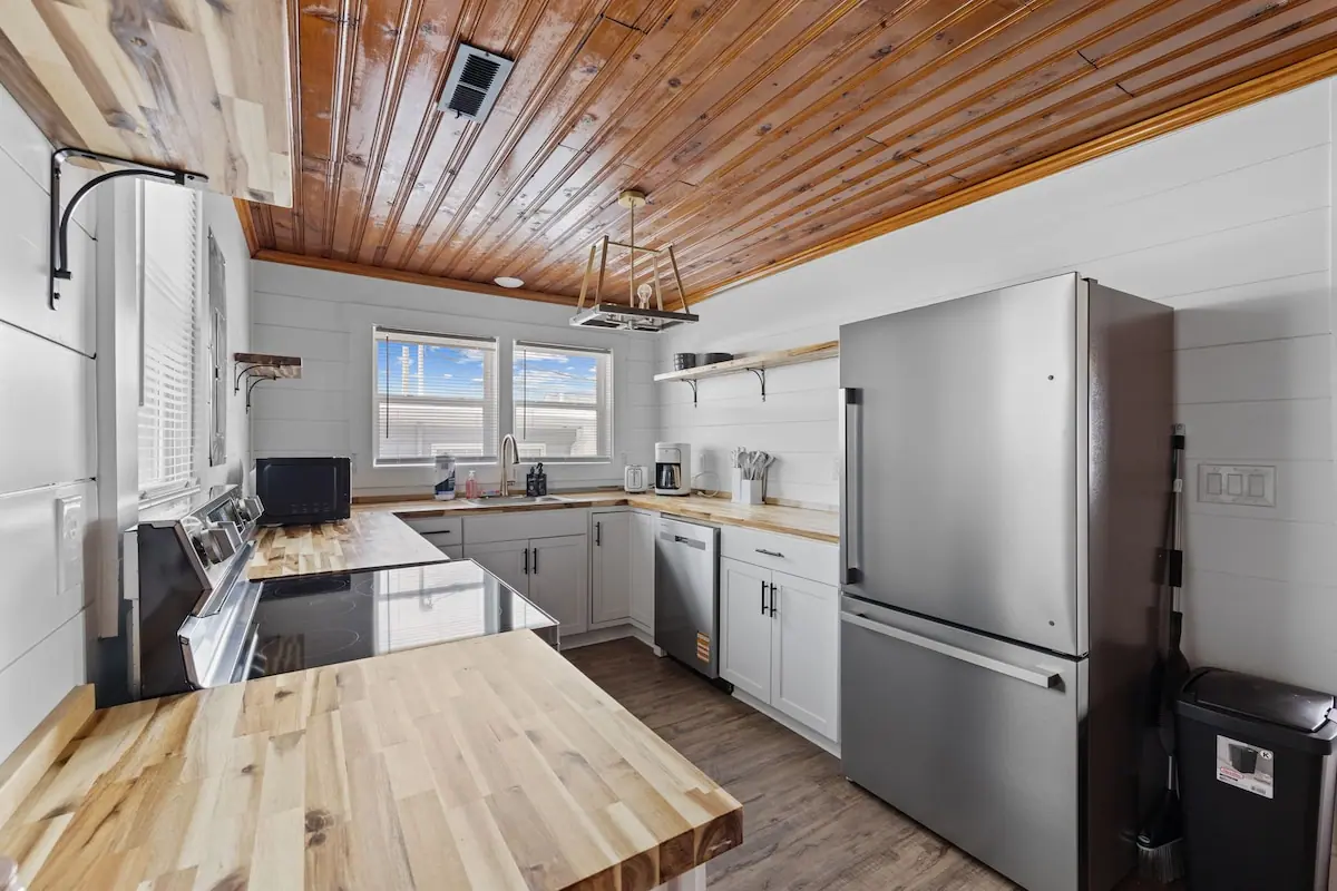 White kitchen with butcher-block counters and a wood-paneled ceiling