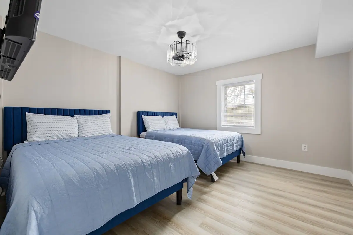 Bedroom with two blue-framed beds, pale blue quilts, and a window