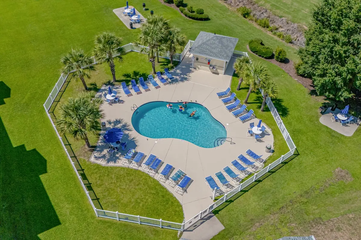 Aerial view of outdoor pool encircled by loungers and lawn