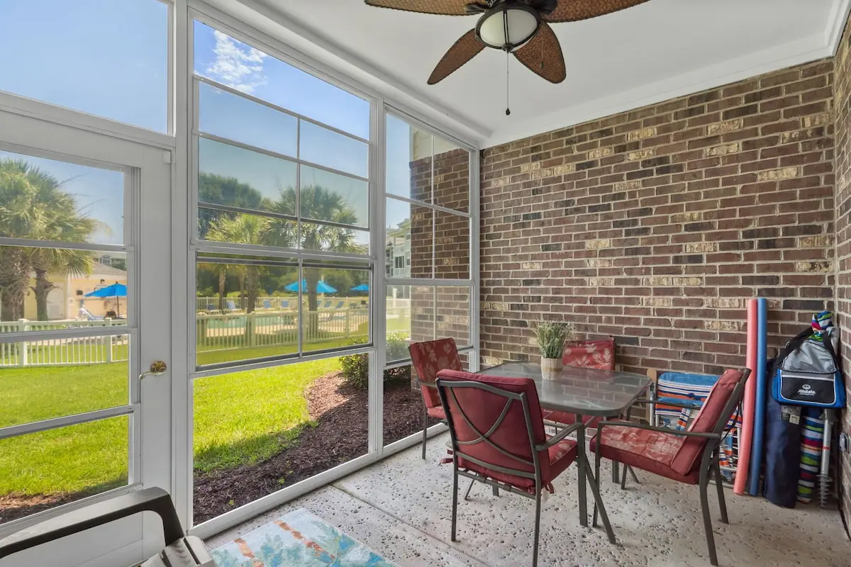 Screened porch with table and red chairs overlooking landscaped yard