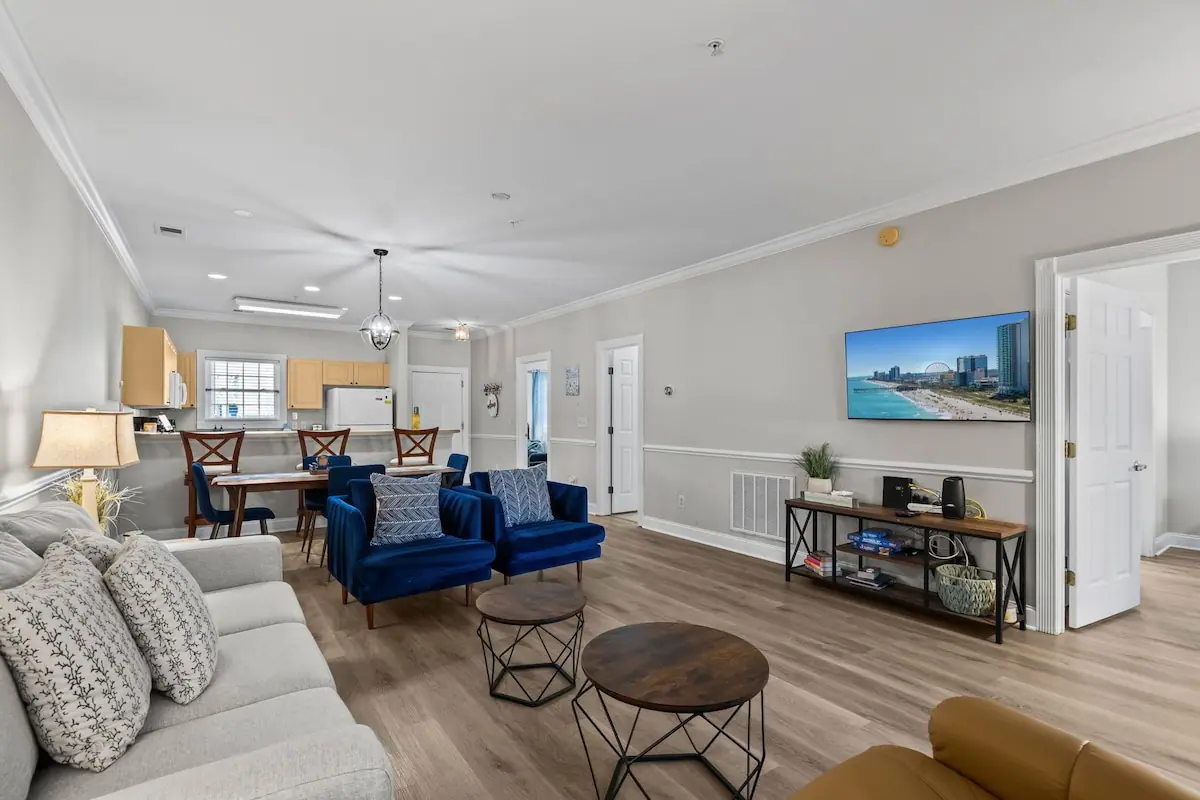 Living room with blue sofas, white couch, and wood floors