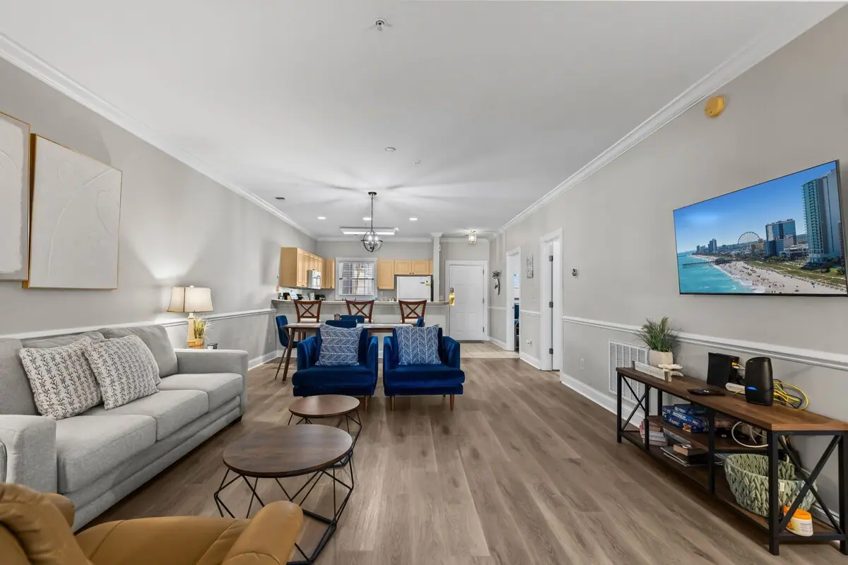 Living area with white couch and blue sofas, dining area beyond