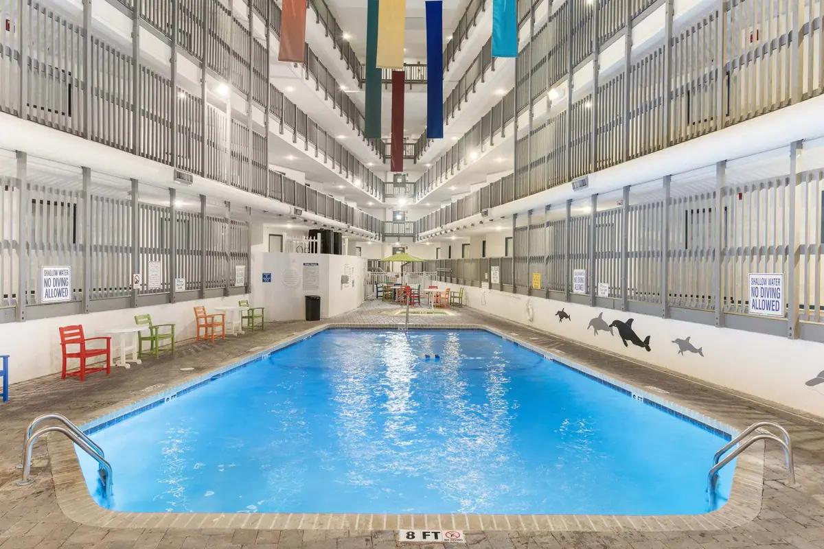Blue indoor swimming pool beneath several levels of balcony railings