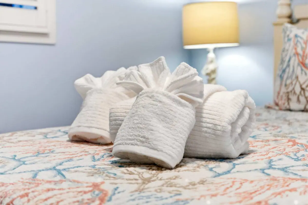 Rolled white towels arranged on a patterned bedspread