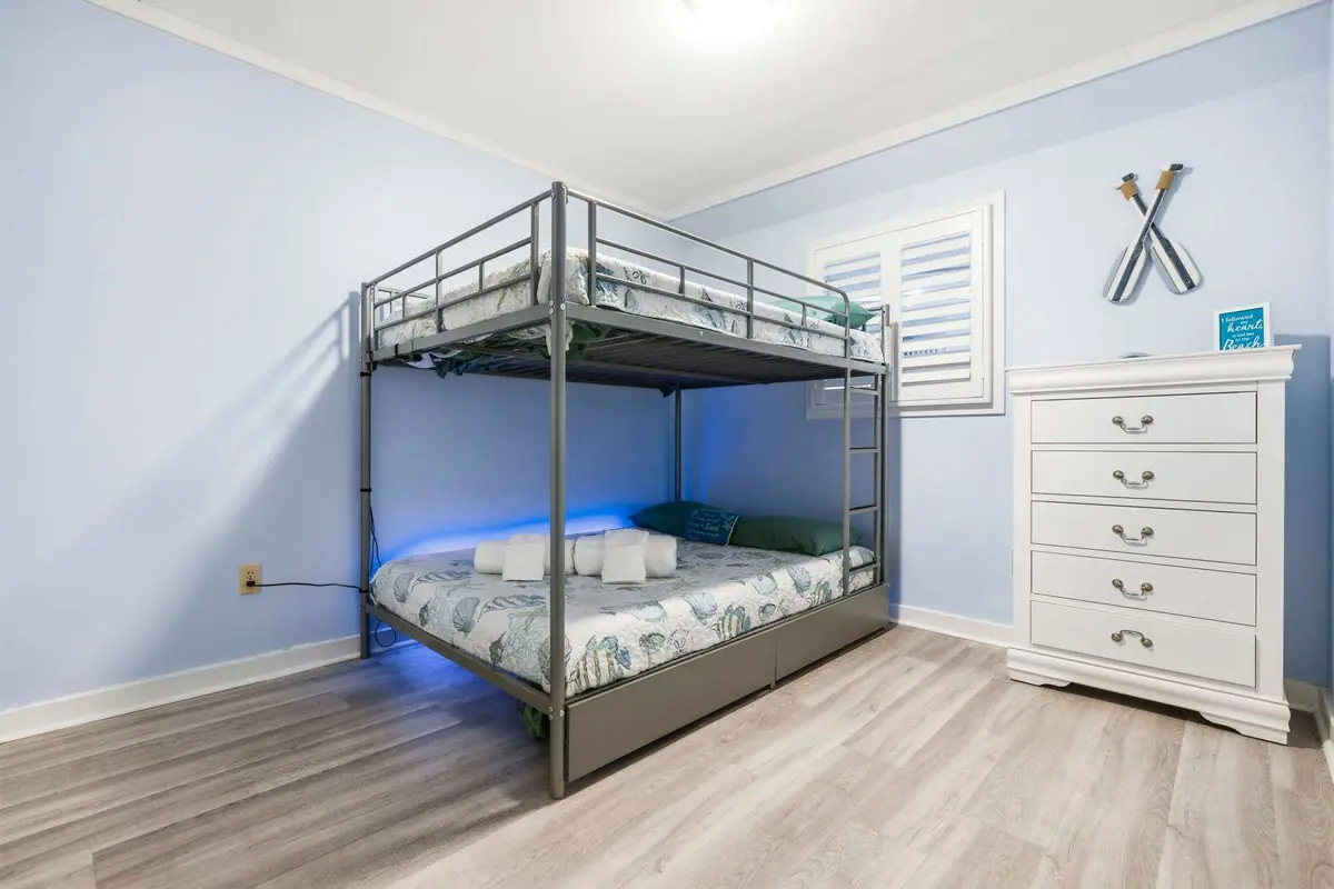 Black metal bunk bed beside a white dresser in a pale blue bedroom
