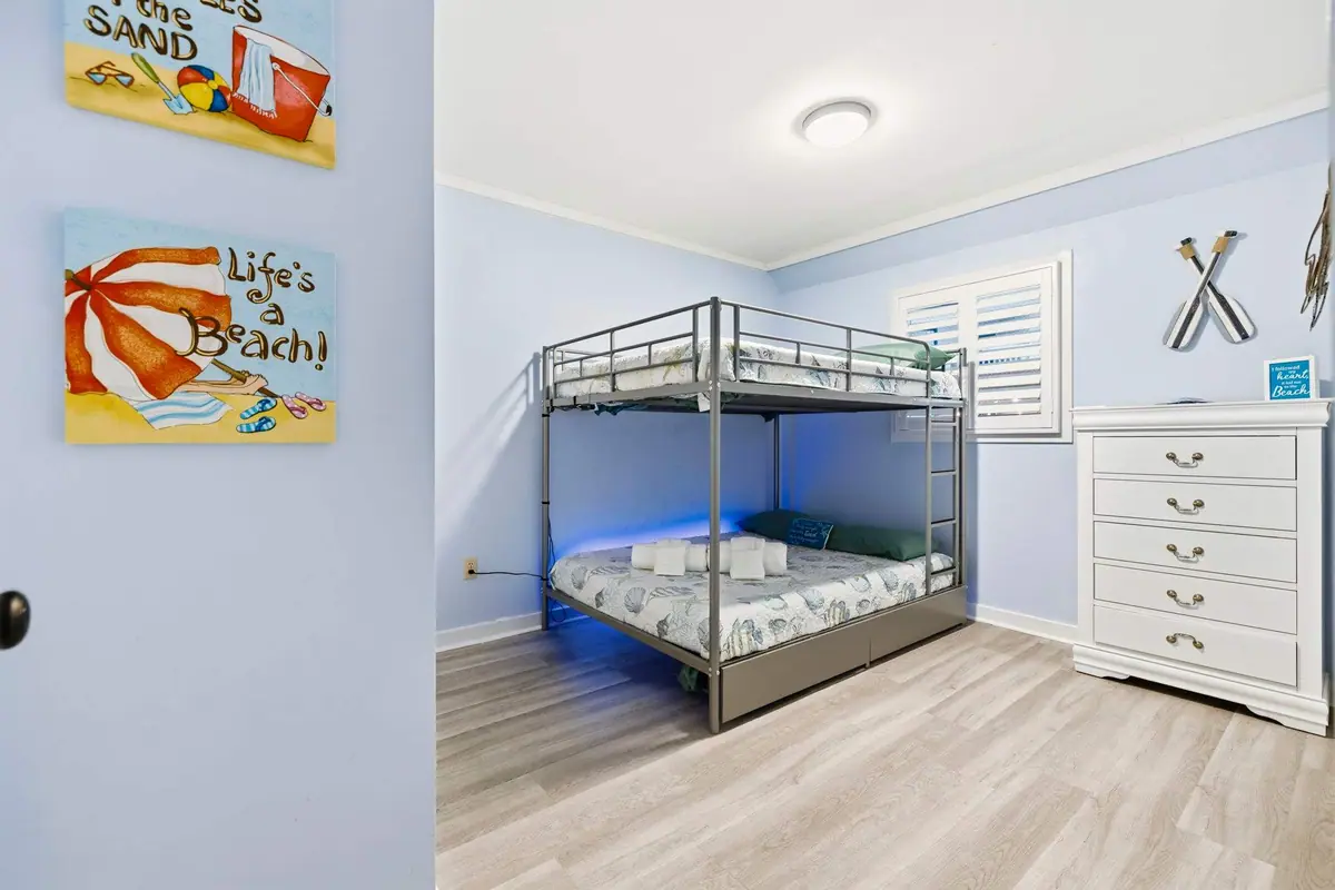 Black metal bunk bed and white dresser beneath beach-themed wall art